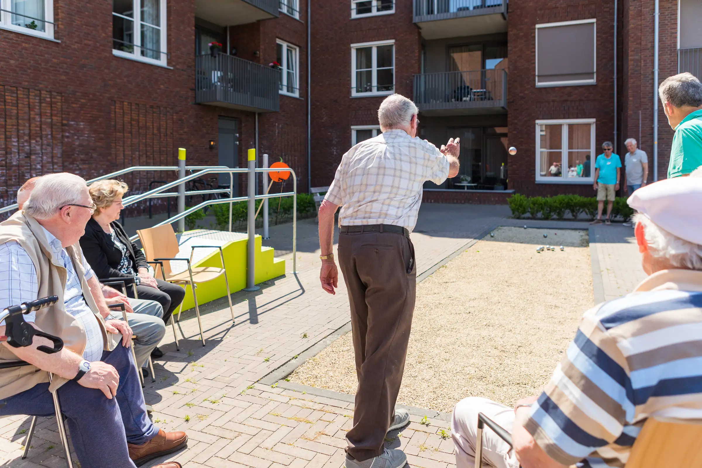 Een groepje ouderen spelen samen jeu de boules of petanque op een zomerse dag.